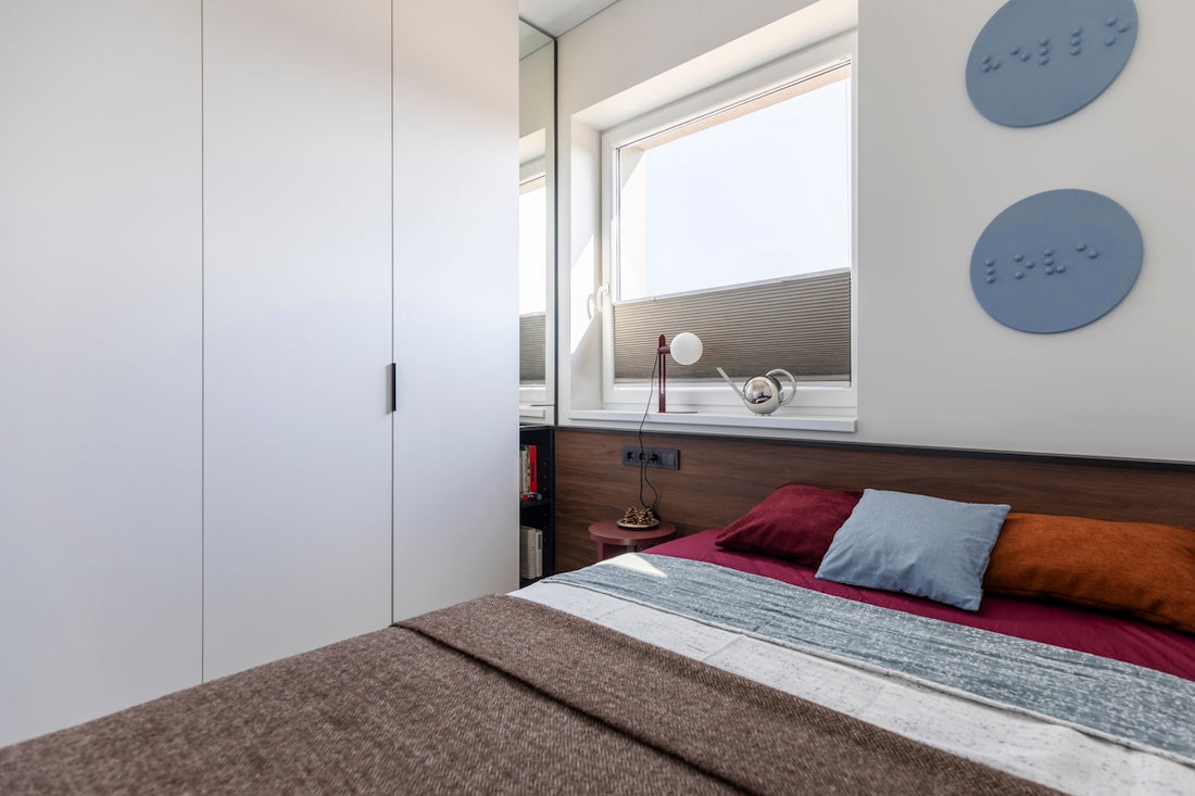 Modern bedroom featuring a bed, white wardrobe, and window.
